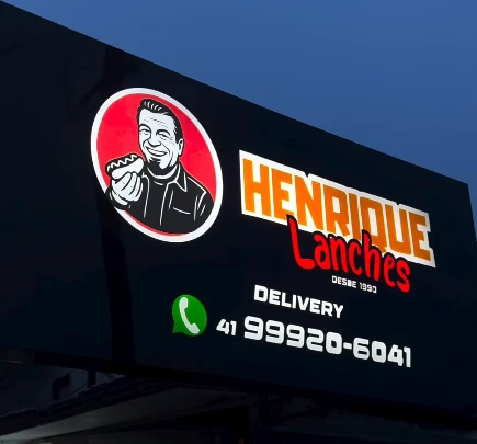 Identificação iluminada Henrique Lanches na fachada comercial